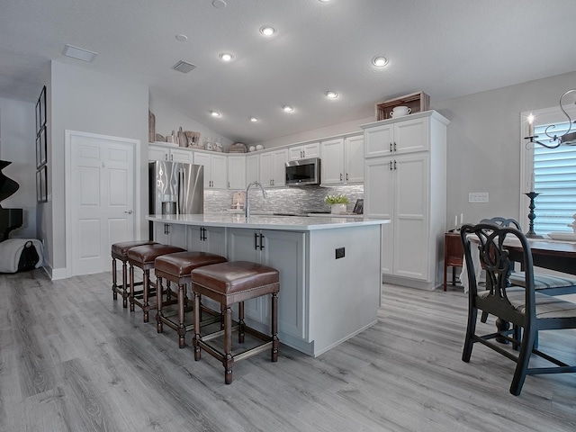 kitchen featuring stainless steel appliances, white cabinetry, and a kitchen island with sink