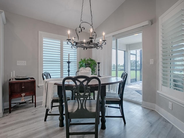 dining space featuring a healthy amount of sunlight, an inviting chandelier, light hardwood / wood-style floors, and vaulted ceiling