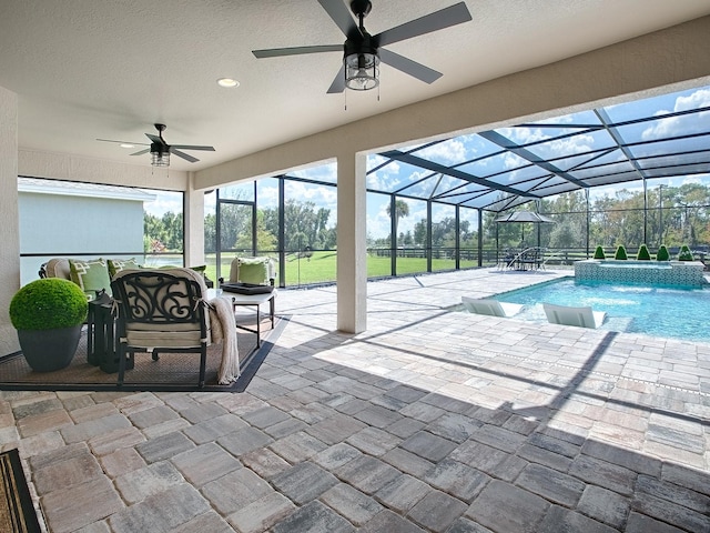 view of swimming pool with pool water feature, ceiling fan, a lanai, and a patio