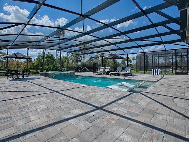 view of pool with glass enclosure, an in ground hot tub, a patio area, and pool water feature