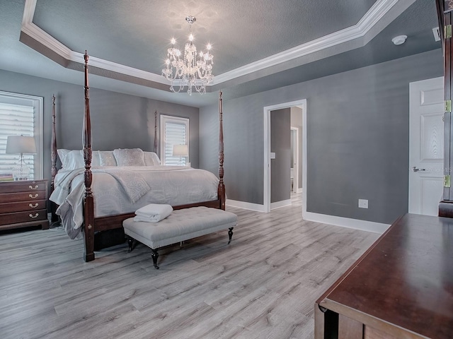 bedroom with a tray ceiling, an inviting chandelier, light hardwood / wood-style floors, and ornamental molding