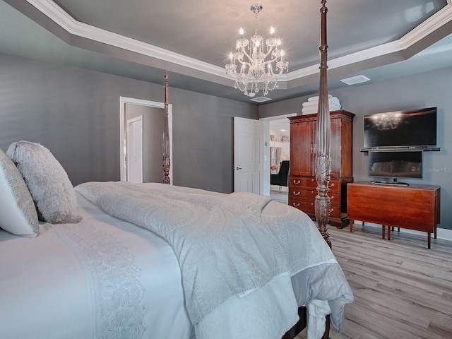 bedroom with light wood-type flooring, a tray ceiling, ornamental molding, and a notable chandelier