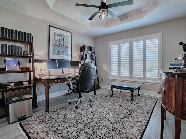 home office featuring a tray ceiling, ceiling fan, light hardwood / wood-style flooring, and crown molding