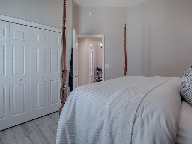 bedroom with high vaulted ceiling, light hardwood / wood-style flooring, and a closet