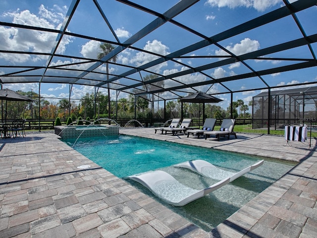 view of pool with pool water feature, glass enclosure, and a patio area