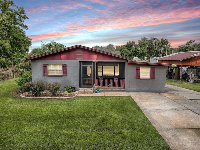 single story home with a lawn, a carport, and a porch