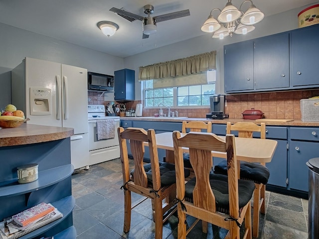 kitchen with blue cabinets, pendant lighting, white appliances, ceiling fan with notable chandelier, and decorative backsplash