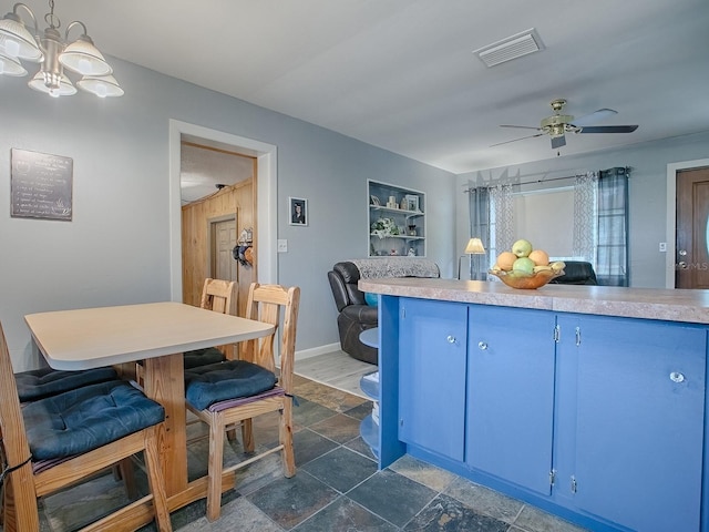 kitchen with hanging light fixtures, ceiling fan with notable chandelier, and blue cabinetry