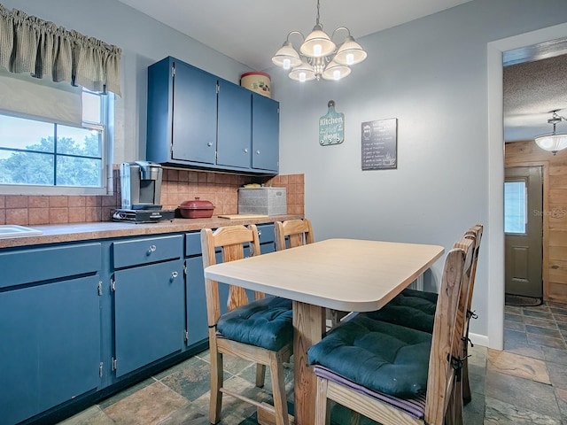 kitchen with decorative backsplash, blue cabinets, a chandelier, and decorative light fixtures