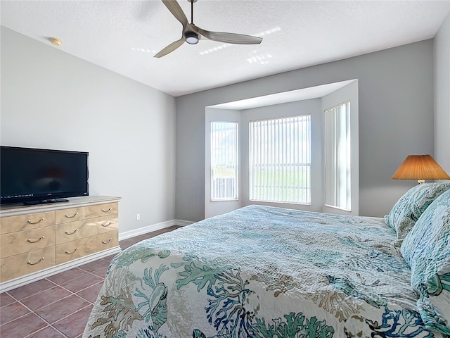 bedroom with ceiling fan, dark tile patterned floors, and a textured ceiling