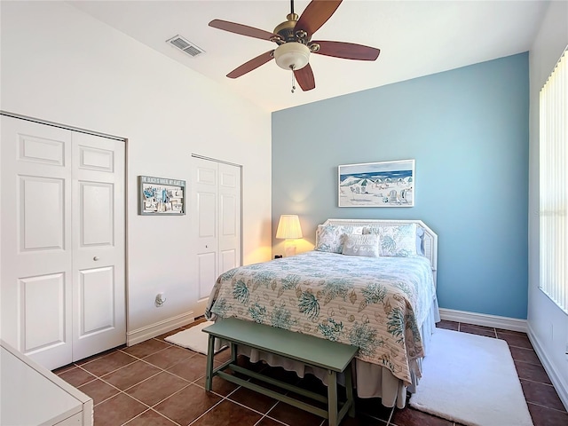 tiled bedroom featuring ceiling fan and multiple closets