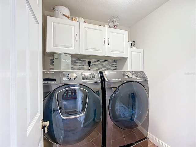 laundry room with washing machine and clothes dryer, tile patterned floors, and cabinets