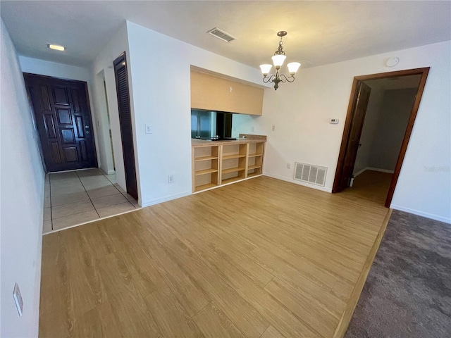 unfurnished living room with a notable chandelier and wood-type flooring