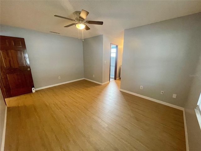 spare room featuring a textured ceiling, light wood-type flooring, and ceiling fan