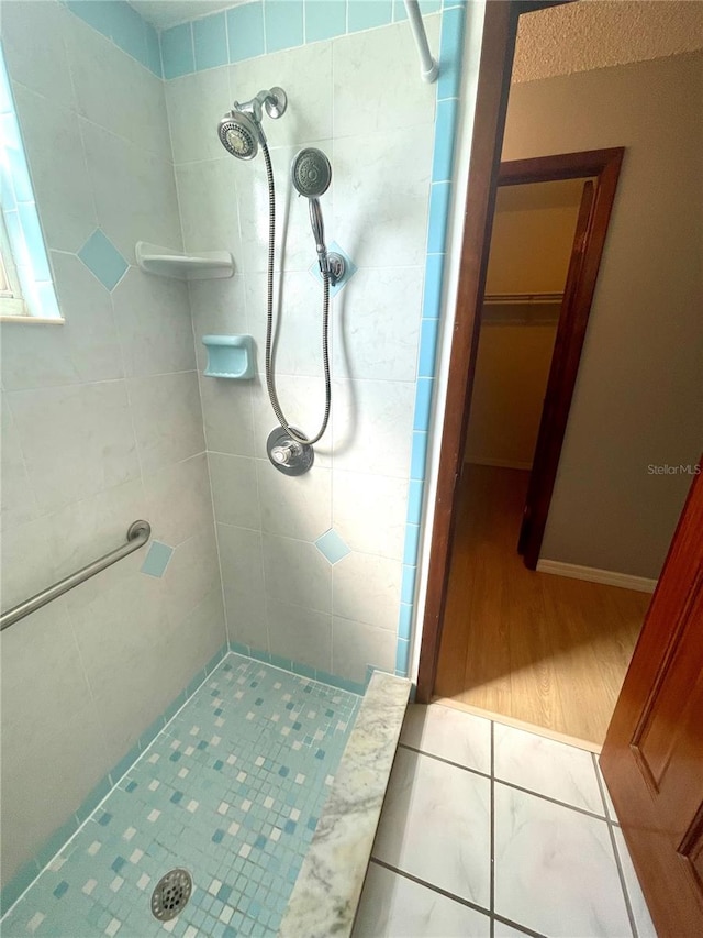 bathroom with tiled shower and wood-type flooring