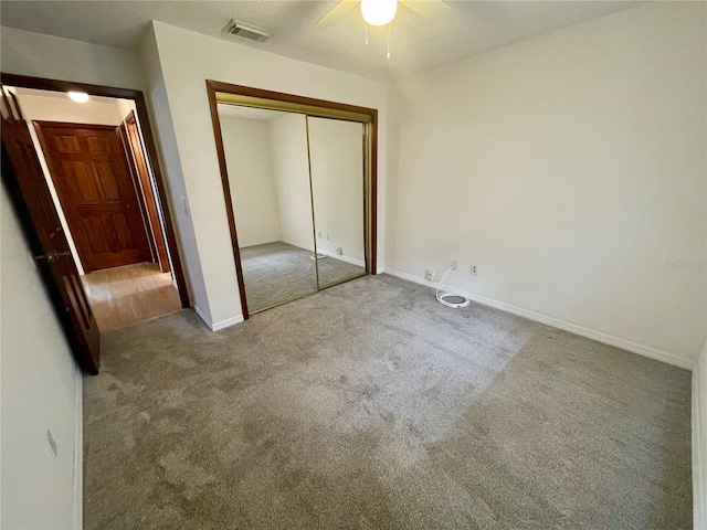 unfurnished bedroom with a closet, light colored carpet, and ceiling fan