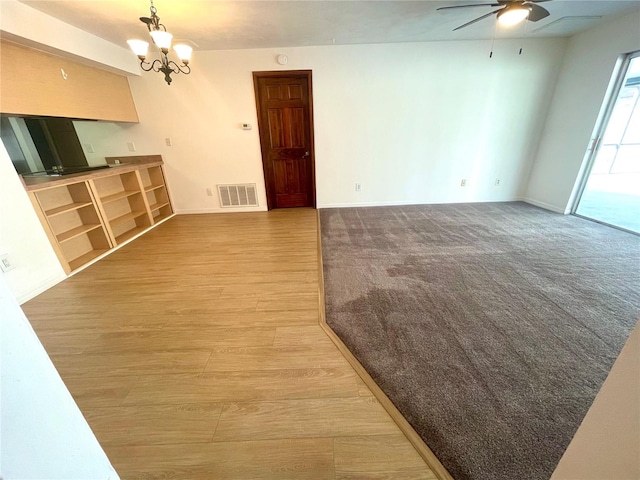 unfurnished living room featuring ceiling fan with notable chandelier and hardwood / wood-style floors