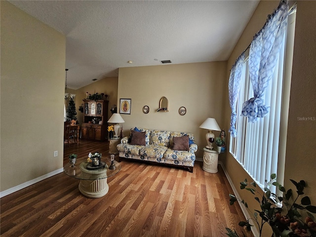 living room with vaulted ceiling, a textured ceiling, and hardwood / wood-style floors