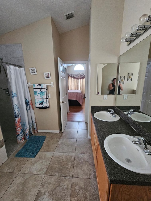 bathroom featuring a textured ceiling, vaulted ceiling, tile patterned floors, vanity, and curtained shower