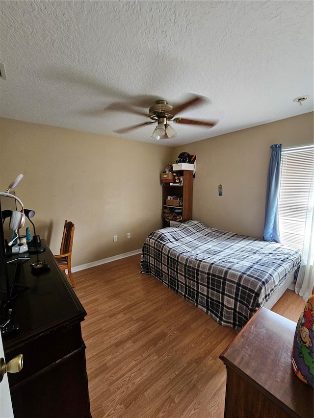 bedroom with ceiling fan, hardwood / wood-style flooring, and a textured ceiling