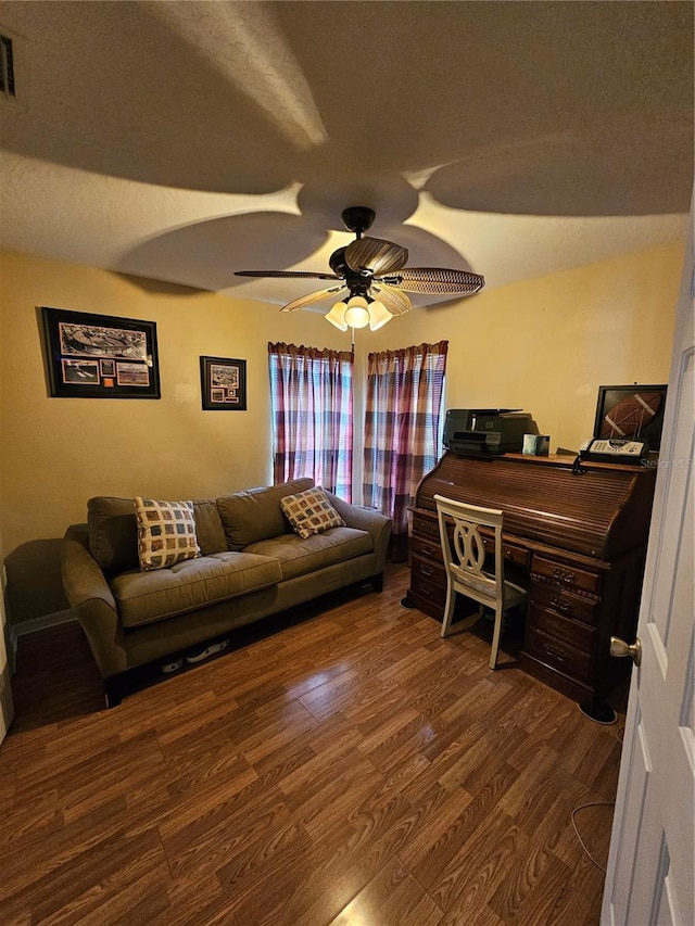 living room with a textured ceiling, dark wood-type flooring, and ceiling fan