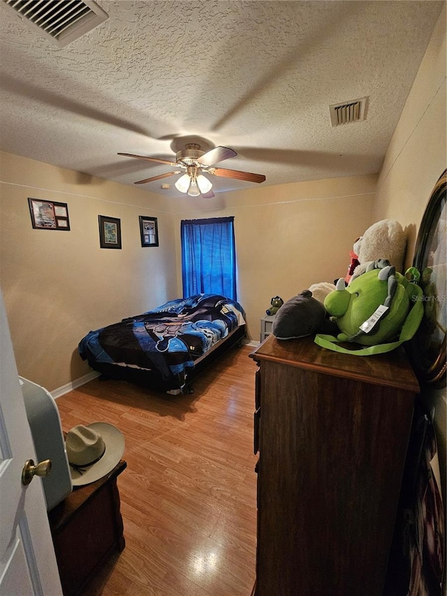 bedroom featuring ceiling fan, a textured ceiling, and light hardwood / wood-style floors