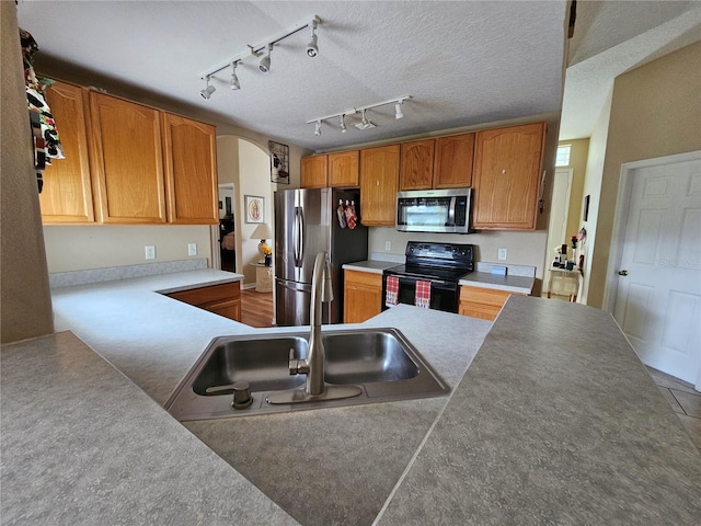 kitchen with stainless steel appliances, rail lighting, a textured ceiling, and sink