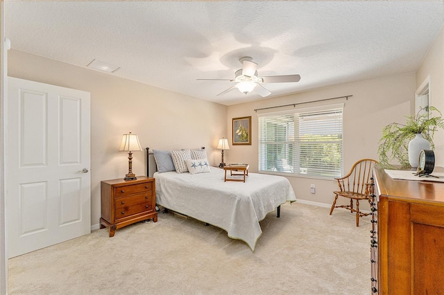 bedroom with ceiling fan, light carpet, and a textured ceiling