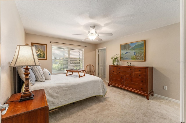 bedroom with ceiling fan, light colored carpet, and a textured ceiling