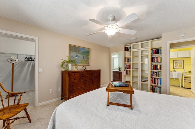 carpeted bedroom with ceiling fan, a textured ceiling, a closet, and ensuite bath