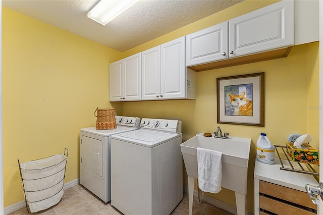 clothes washing area featuring washing machine and dryer, cabinets, a textured ceiling, and sink