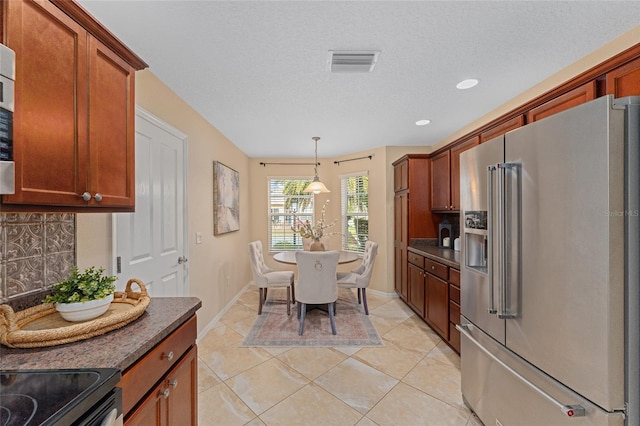 kitchen featuring a textured ceiling, decorative light fixtures, tasteful backsplash, light tile patterned flooring, and high end fridge