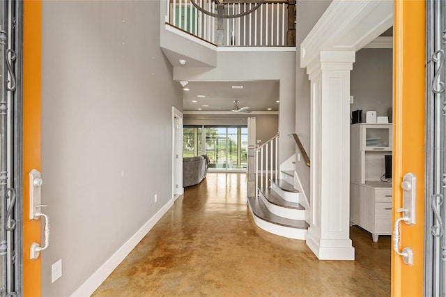 entryway with ceiling fan, crown molding, a high ceiling, and concrete floors