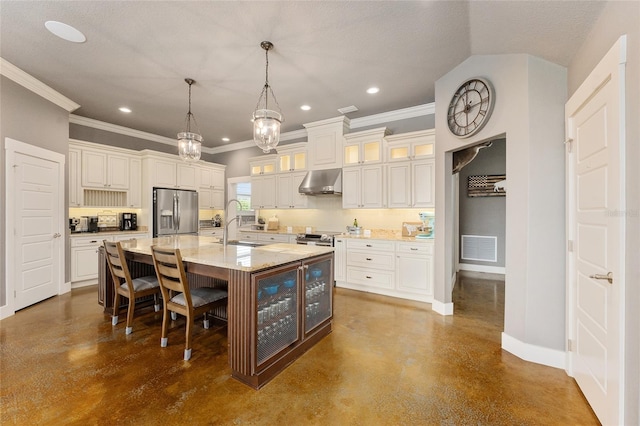 kitchen with hanging light fixtures, tasteful backsplash, a center island with sink, extractor fan, and appliances with stainless steel finishes