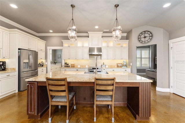 kitchen with appliances with stainless steel finishes, wall chimney exhaust hood, hanging light fixtures, and a center island with sink