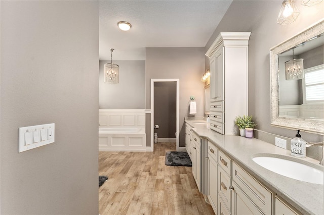 bathroom with an inviting chandelier, hardwood / wood-style flooring, vanity, and toilet