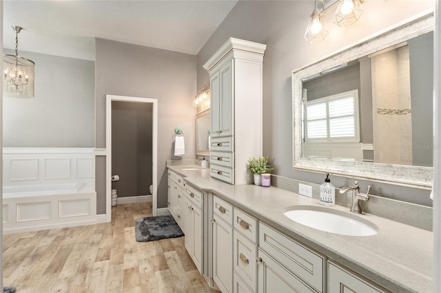 bathroom with hardwood / wood-style floors, a tub, vanity, and toilet