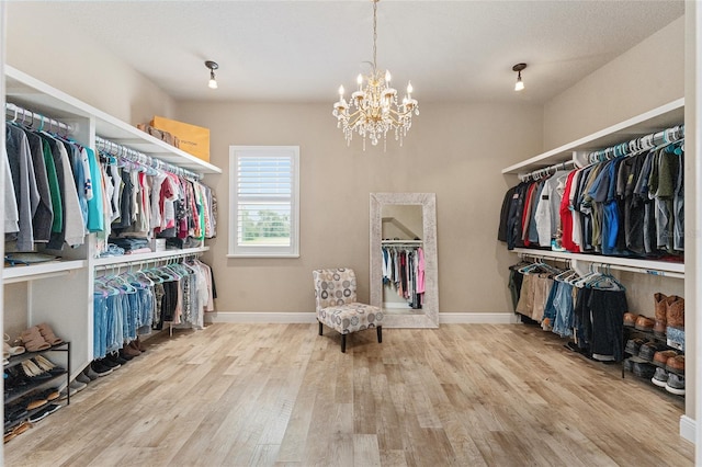 spacious closet with wood-type flooring and an inviting chandelier