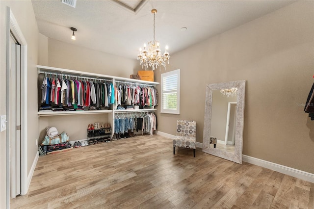 spacious closet featuring hardwood / wood-style flooring and a notable chandelier