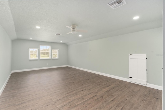 empty room featuring lofted ceiling, ceiling fan, hardwood / wood-style floors, and a textured ceiling