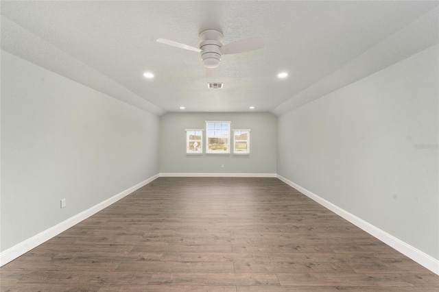 spare room with dark wood-type flooring, ceiling fan, lofted ceiling, and a textured ceiling