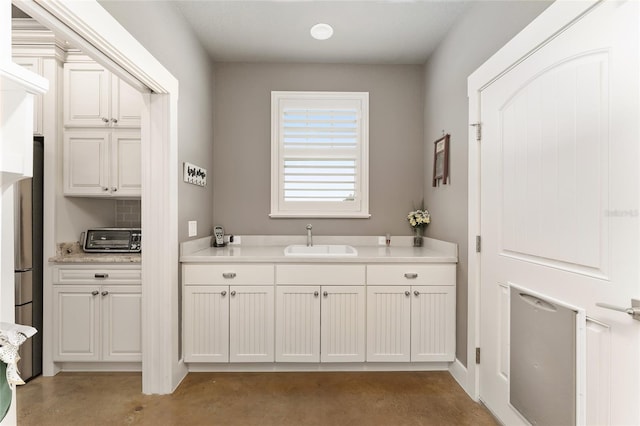 interior space featuring backsplash, sink, and white cabinetry