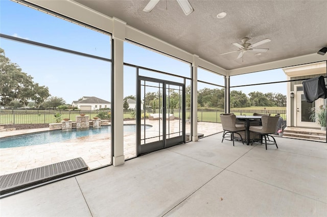 unfurnished sunroom featuring ceiling fan