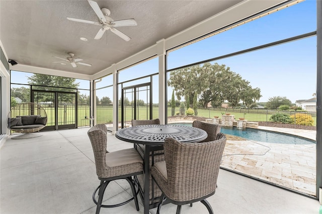 sunroom / solarium featuring ceiling fan, a pool, and a wealth of natural light