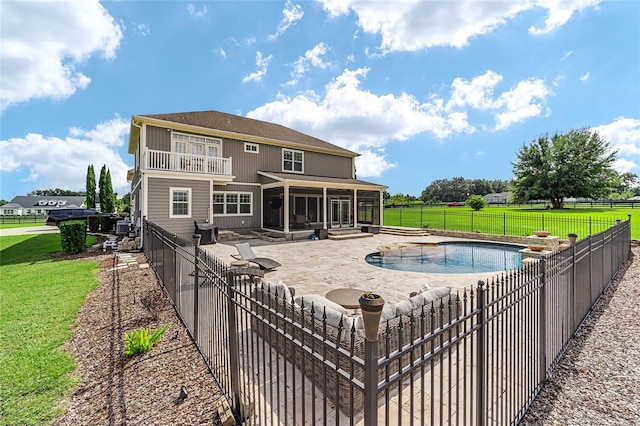 back of house with a fenced in pool, a patio, a yard, and a sunroom