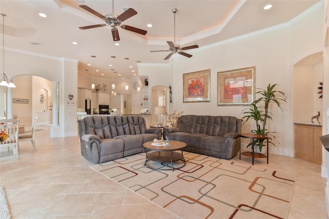 living room with ornamental molding, a raised ceiling, a towering ceiling, and ceiling fan