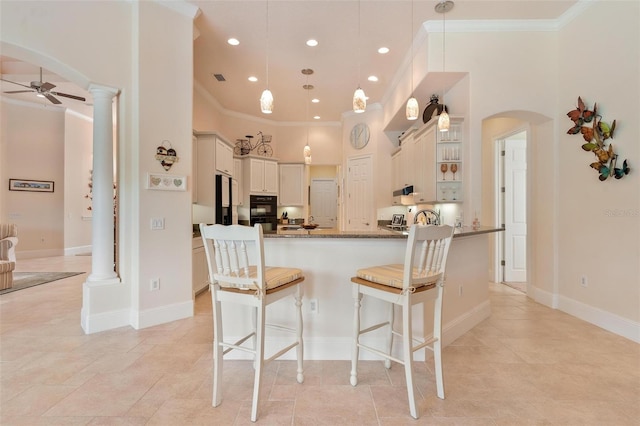 kitchen with a towering ceiling, hanging light fixtures, and ornate columns