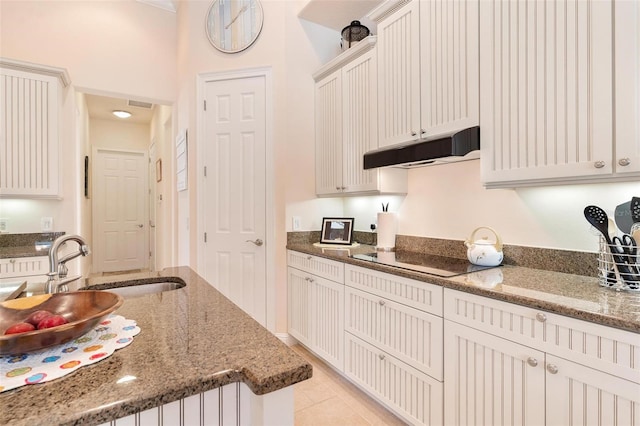 kitchen with white cabinetry, light tile patterned floors, dark stone counters, and electric stovetop