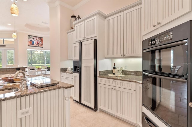 kitchen with paneled refrigerator, sink, pendant lighting, and black double oven