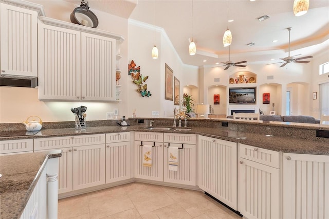 kitchen featuring sink, white cabinetry, decorative light fixtures, and a tray ceiling